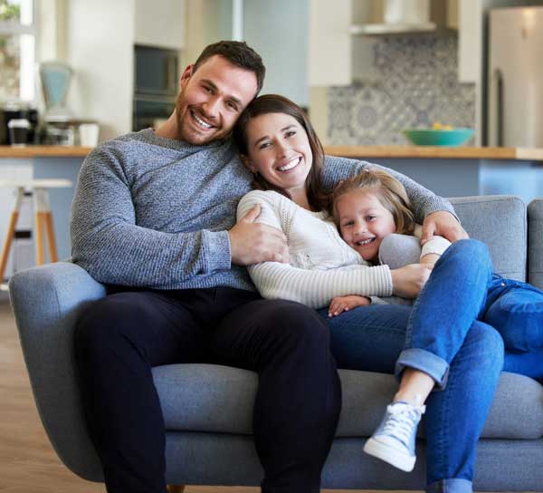 A Family smiling and sitting comfortable in their home