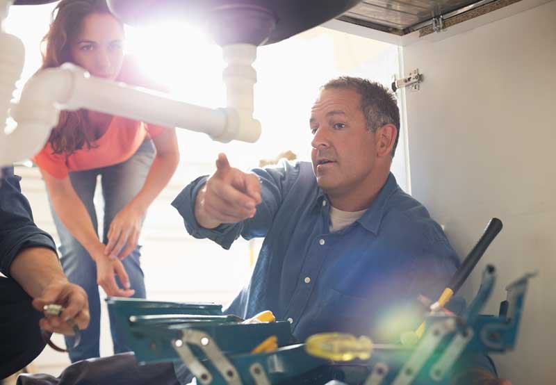Plumber showing a client the issue under a sink